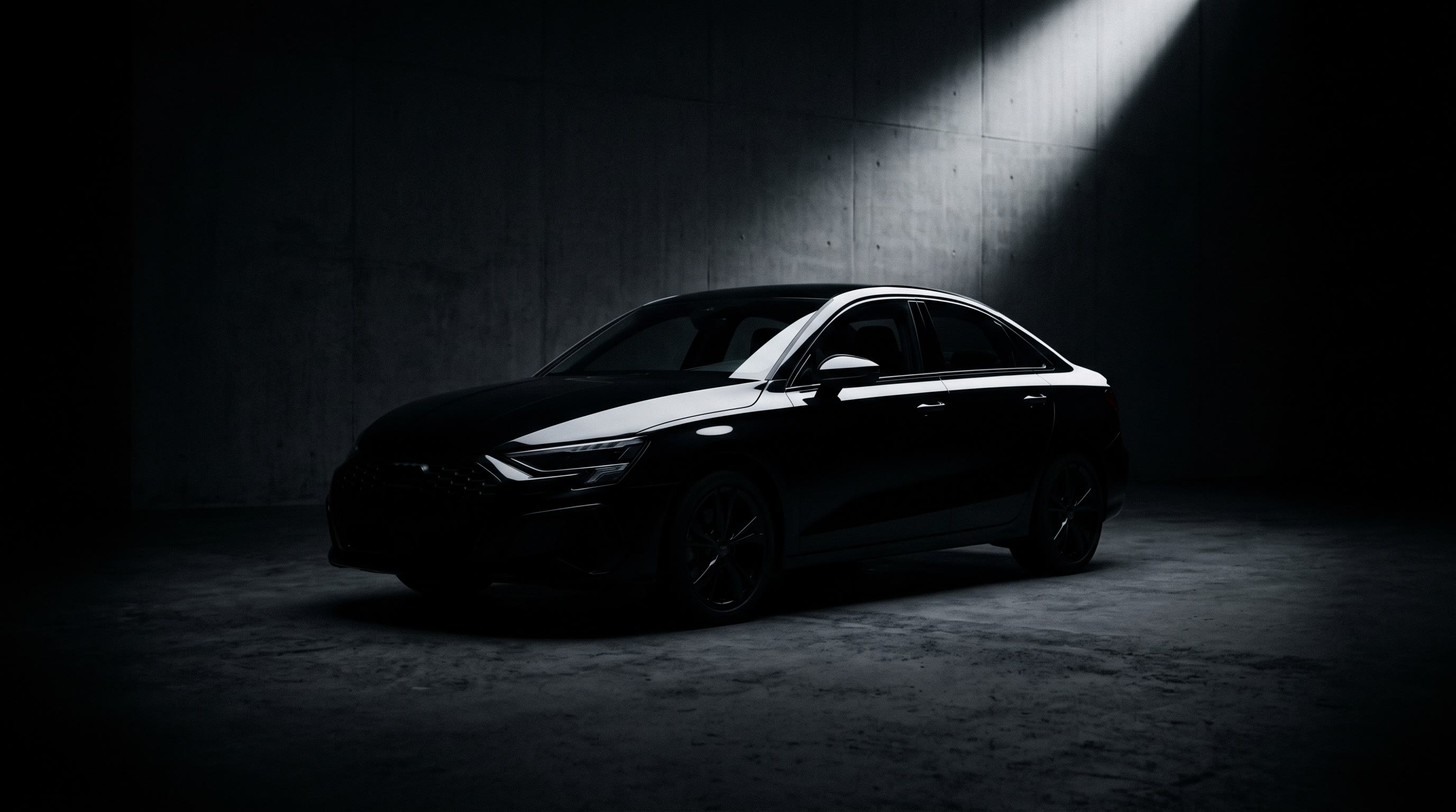 Black training sedan in a dark studio under a single beam of light